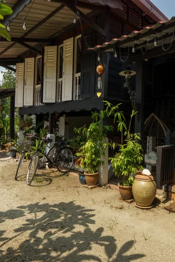 Rumah Teduh Langkawi – Wooden Veranda Traditional wooden veranda and outdoor staircase at Rumah Teduh Langkawi, surrounded by tropical plants.