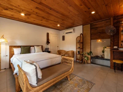 Wooden cabin bedroom with a king-size bed, rattan furniture and kitchenette in Langkawi
