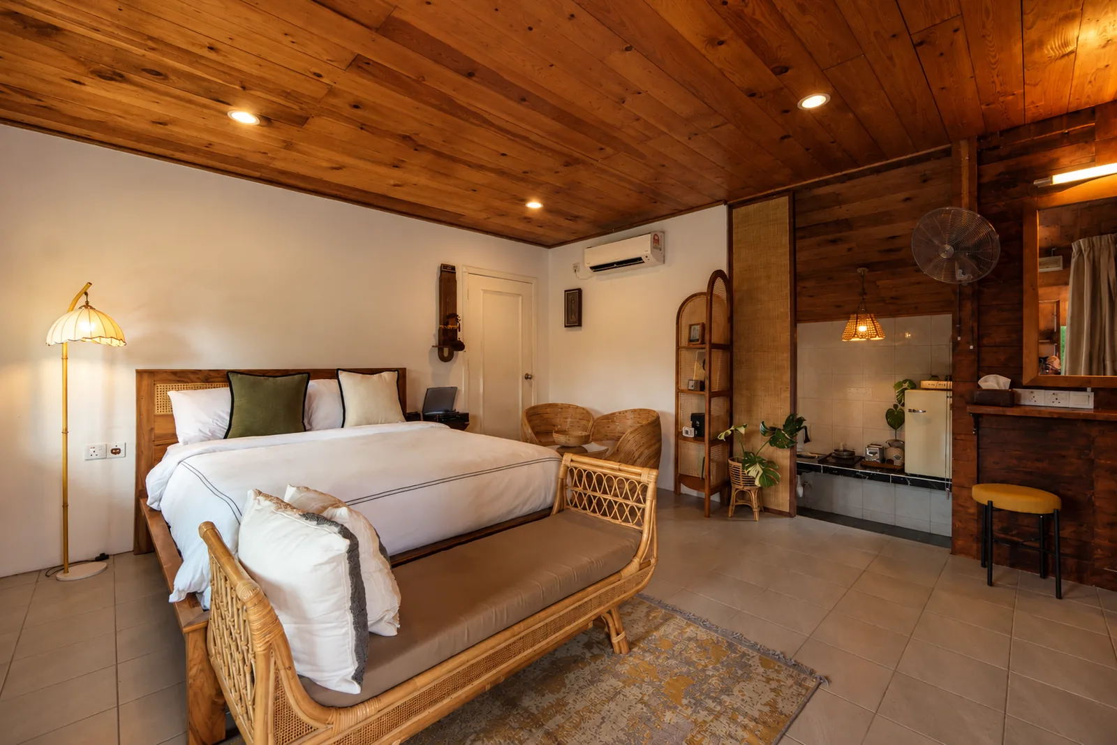 Wooden cabin bedroom with a king-size bed, rattan furniture and kitchenette in Langkawi